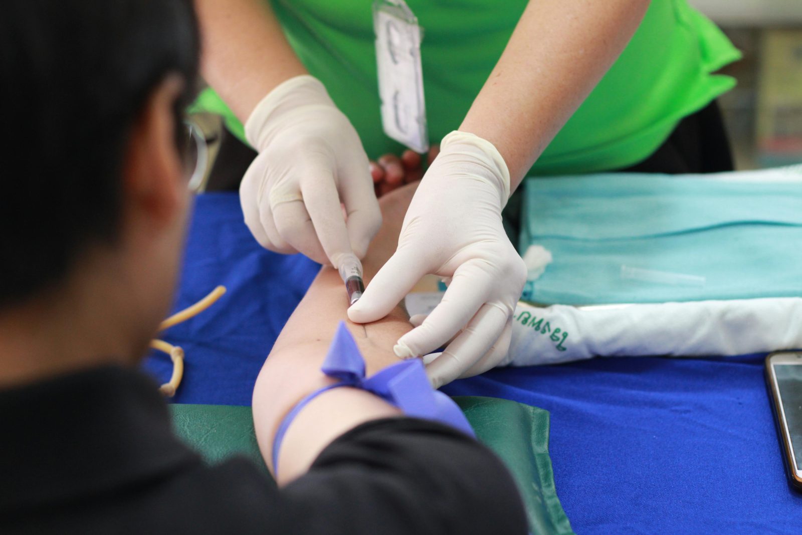 A doctor drawing blood from a young man's arm as part of a paid clinical trial in NZ.