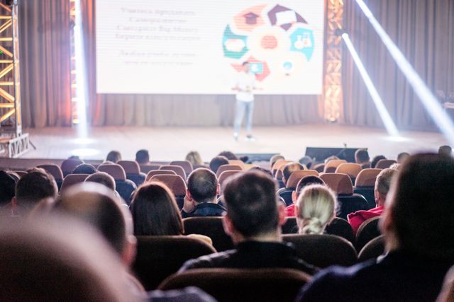 speaker on stage while conference attendees are seated